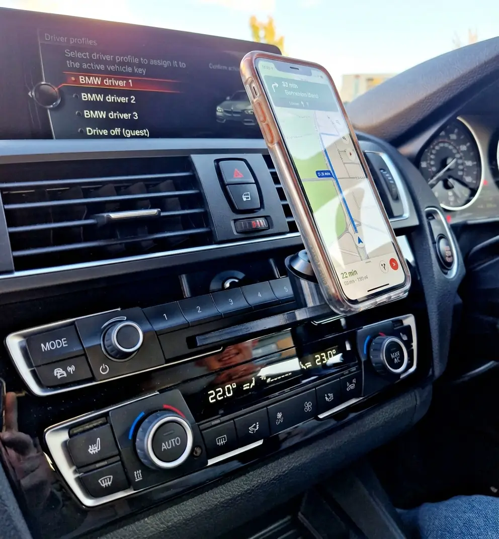 A smartphone displaying GPS navigation securely attached to a custom magnetic CD slot mount in a BMW dashboard.